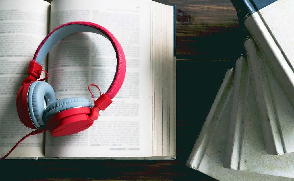Headphones sitting on a book Audiobook Recording Guide